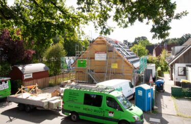 Photovoltaikinstallation bei einem Einfamilienhaus. im Vordergrund stehen zwei Firmenwagen und ein Dixi-Klo. Um das Haus ist ein Gerüst gebaut.