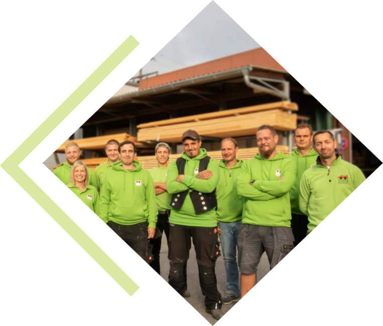 Teamfoto draußen auf dem Firmengelände. Im Hintergrund viele geordnete und aufeinander gestapeltes Holz.