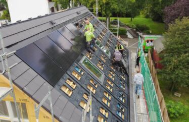 Drohnenaufnahme von oben. Mitarbeiter auf dem Dach für eine Photovoltaik-Installation